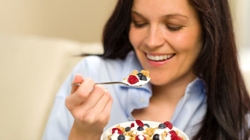 Mujer desayunando cereales con fruta